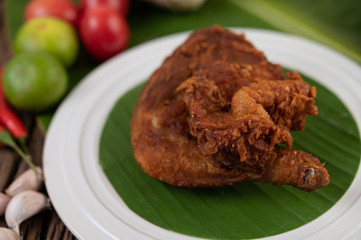 Chicken thighs fried on banana leaves on a white plate