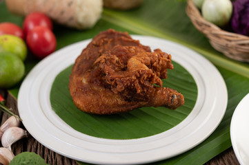 Chicken thighs fried on banana leaves on a white plate
