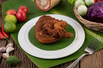 Chicken thighs fried on banana leaves on a white plate