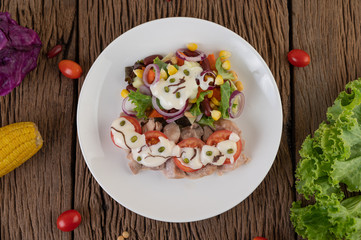 Fruit and vegetable salad on a white plate on a wooden floor