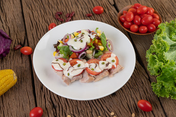Fruit and vegetable salad on a white plate on a wooden floor