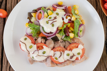 Fruit and vegetable salad on a white plate on a wooden floor