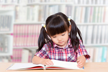 図書館で読書する幼い女の子。読書、勉強、興味、集中イメージ