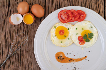 Fried egg on a white plate with sliced ​​Spring onion and sliced ​​tomatoes