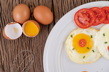 Fried egg on a white plate with sliced ​​Spring onion and sliced ​​tomatoes