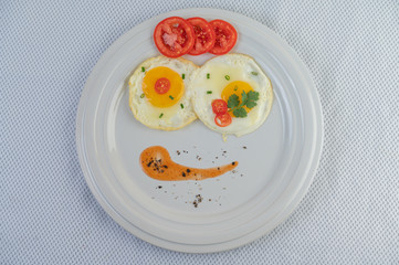 Fried egg on a white plate with sliced ​​Spring onion and sliced ​​tomatoes