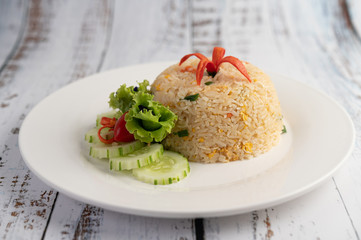 Fried rice with eggs in a white plate on wood background.