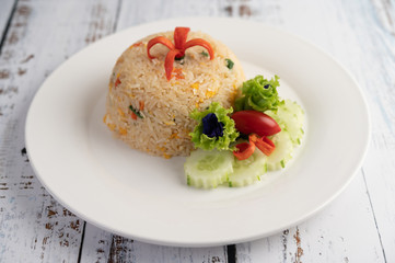 Fried rice with eggs in a white plate on wood background.