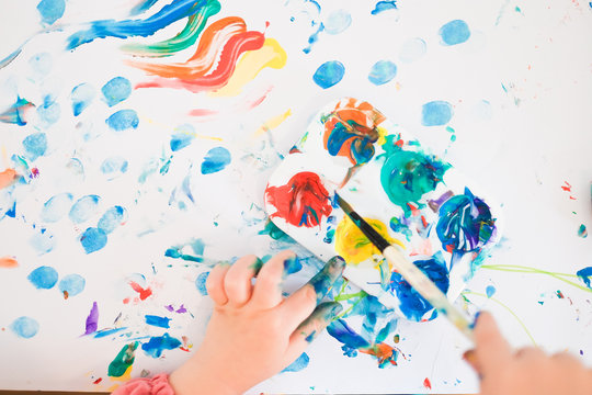 A Child Is Painting With Fingers And Brush And Oil Paints