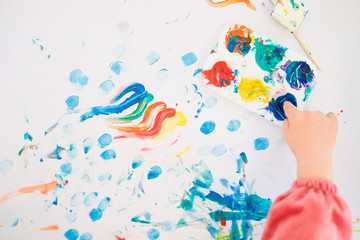 A child is painting with fingers and brush and oil paints