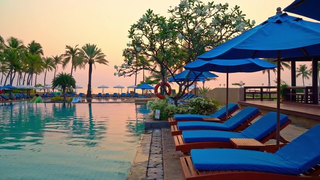 bed pool and umbrella around swimming pool with sunset or sunrise sky