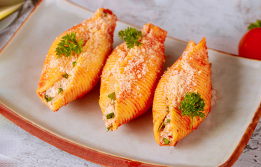 Pasta shells stuffed with ricotta, meat and parmesan on plate.