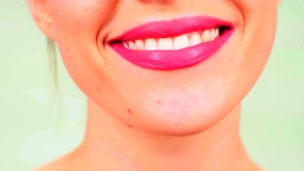 Le sourire d'une jeune femme avec du rouge à lèvres et des dents blanches