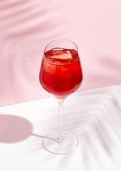 Red summer cocktail in wine glass on creative background