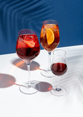 Summer cocktails on creative background. Shadows of palm leaf on classic blue wall