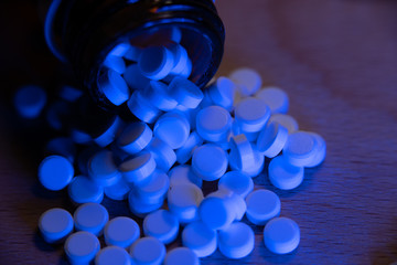 White pills under blue light. Medicine and health supplements. Medical bottle pharmaceuticals for...