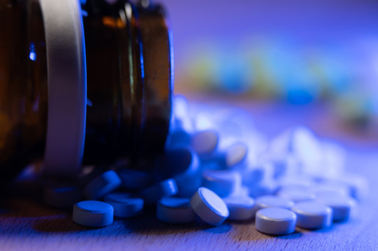 Prescription drugs in form of tablets. Bottle and pills out of focus. Medicine and Healthcare. Large amount of pills and tablets