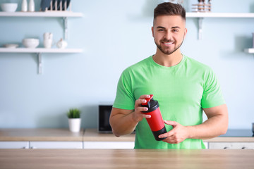 Sporty man with protein shake in kitchen