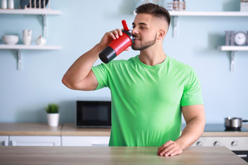 Sporty man with protein shake in kitchen
