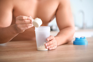 Fototapeta na wymiar Sporty man making protein shake at home, closeup