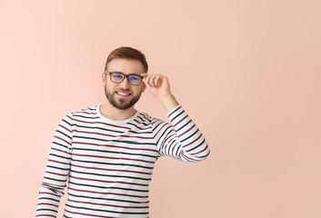 Young man with stylish eyeglasses on color background