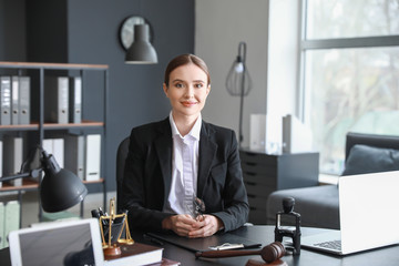 Female lawyer sitting at workplace in office - obrazy, fototapety, plakaty