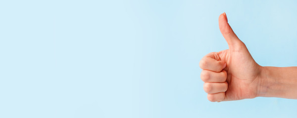 Closeup of female hand showing thumbs up sign against pastel blue background, copy space, minimal concept - 331112829