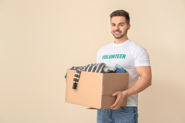 Volunteer with donations for poor people on color background