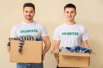 Volunteers with donations for poor people on color background
