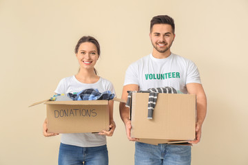 Volunteers with donations for poor people on color background
