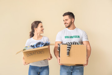 Volunteers with donations for poor people on color background