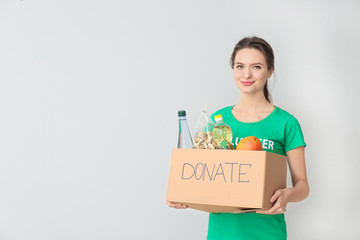 Volunteer with donations for poor people on light background