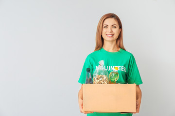 Volunteer with donations for poor people on light background