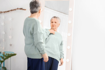 Happy senior woman looking at her reflection in mirror