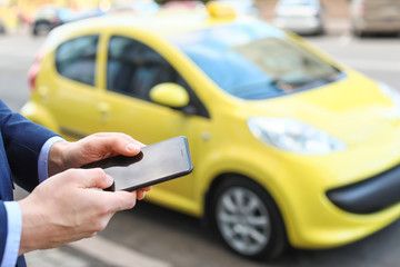 Businessman with mobile phone calling taxi outdoors, closeup