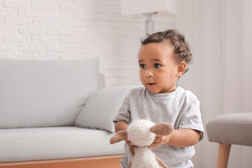 Cute African-American baby with toy at home