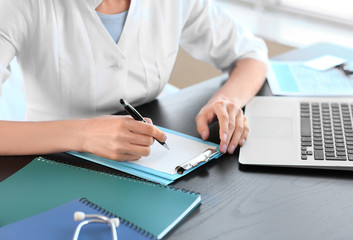 Fototapeta premium Young female doctor working in clinic, closeup