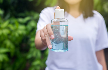 Woman hands holding sanitizer gel in pump bottle for hand hygiene coronavirus protection at outdoor