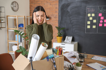 Sad fired woman with personal stuff in office