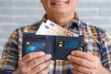 Senior man with purse on brick background, closeup