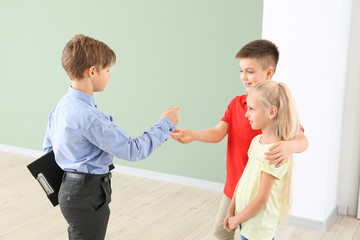 Little real estate giving a key from new house to clients indoors