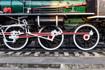 Old train wheels on rails in black, red and white.