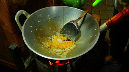 Cooking Nasi Goreng or Indonesian fried rice with egg