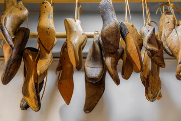 Selection of Italian footwear shoe and boot forms or lasts for shoemaking hanging in a leather...