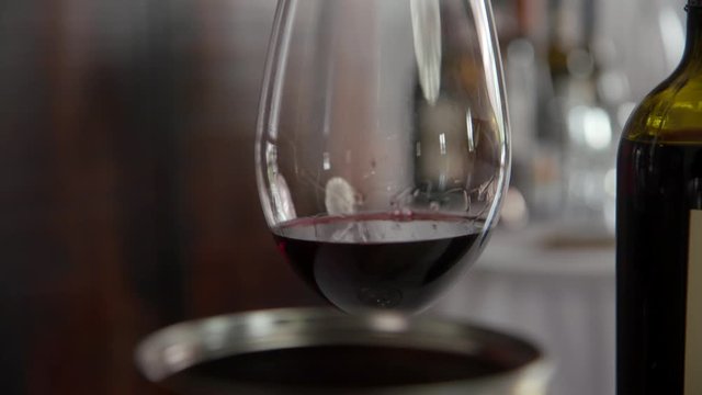 Primitivo red wine with wine legs and tears showing the viscosity of the wine in the glass in slow motion 4k footage.