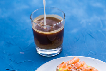 Morning and breakfast concept - Pouring cream into a cup of coffee