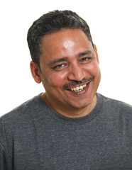 An Indian man smiling to camera. Shot against a white background.