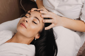 Caucasian masseur having a spa procedure of head massage with brunette charming lady