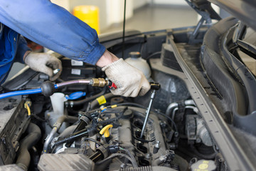 Car repair at a service station. The hands of a professional mechanic hold a tool. Spark Plug...
