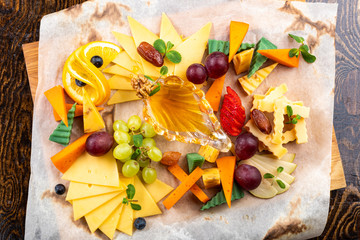 cheese slices with grapes and fruits on paper and wooden background